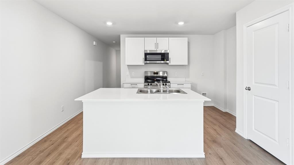 3519 Spring Time Street Forney, TX 75126 - Photo 26 of 37 Modern kitchen featuring a white island with an undermount double-basin sink, stainless steel faucet, and solid surface countertop