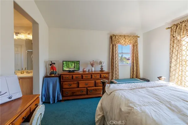 a bedroom with a bed table chair and a large window