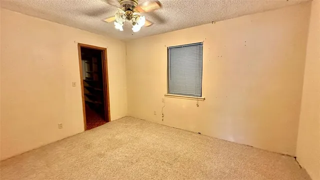 an empty room with a chandelier fan and windows