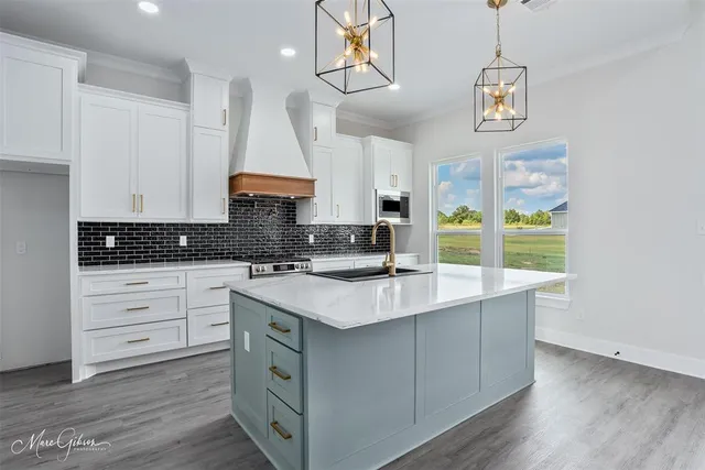 a kitchen with a sink dishwasher a stove and white cabinets with wooden floor