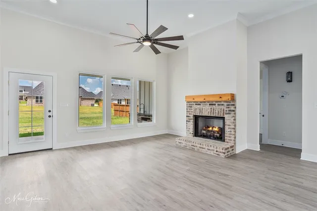 a large kitchen with stainless steel appliances granite countertop a stove a sink a refrigerator and white cabinets with wooden floor