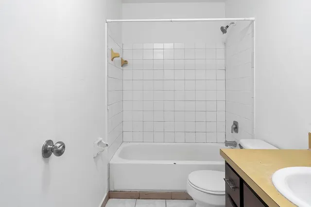 a bathroom with a granite countertop bathtub shower sink vanity and toilet
