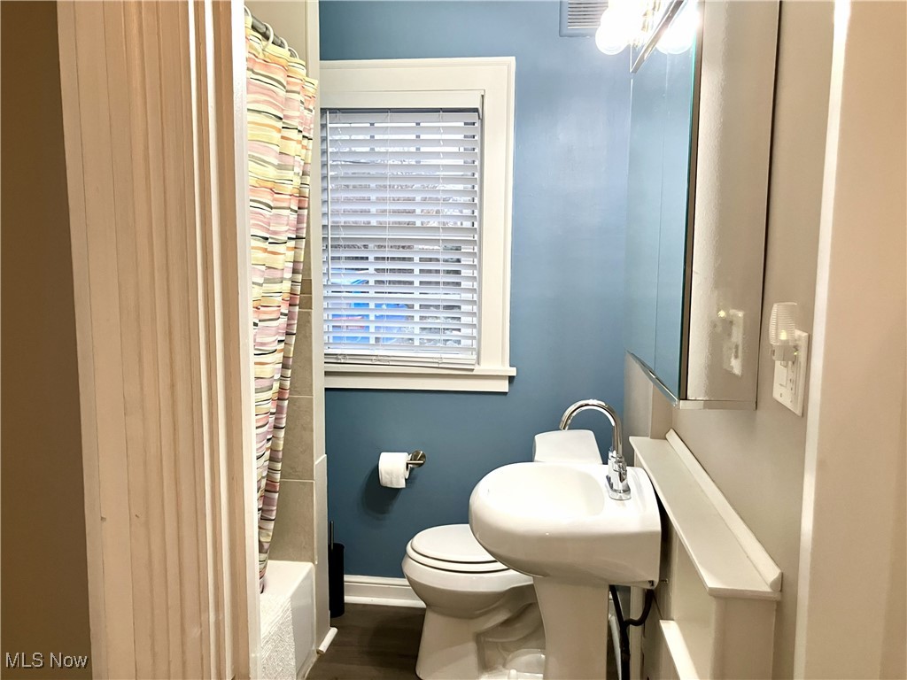 1006 Ridge Road Northwest Canton, OH 44703 - Photo 11 of 22 Bathroom featuring shower / bath combo with shower curtain and dark wood finished floors