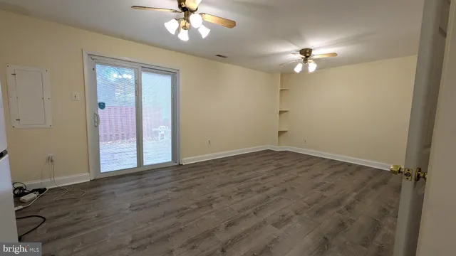 wooden floor in an empty room with a chandelier fan
