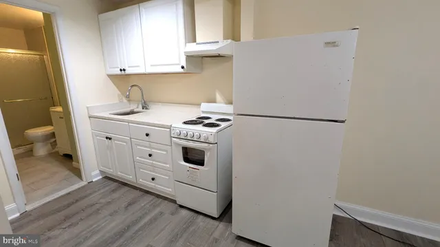 a kitchen with a stove white cabinetry and a sink