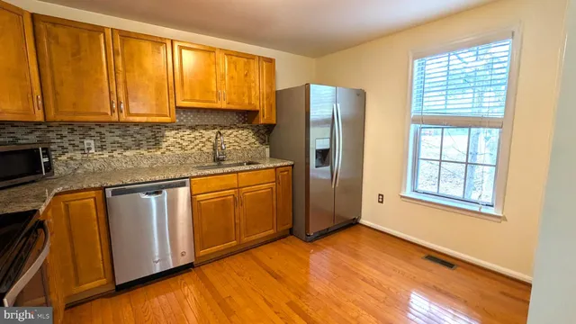a kitchen with stainless steel appliances granite countertop cabinets and wooden floor