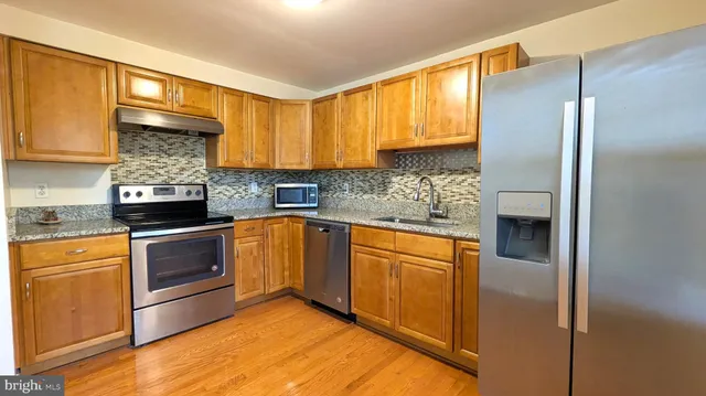 a kitchen with stainless steel appliances granite countertop a refrigerator a sink dishwasher a stove and a microwave oven