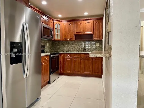 a kitchen with stainless steel appliances granite countertop a refrigerator and a sink