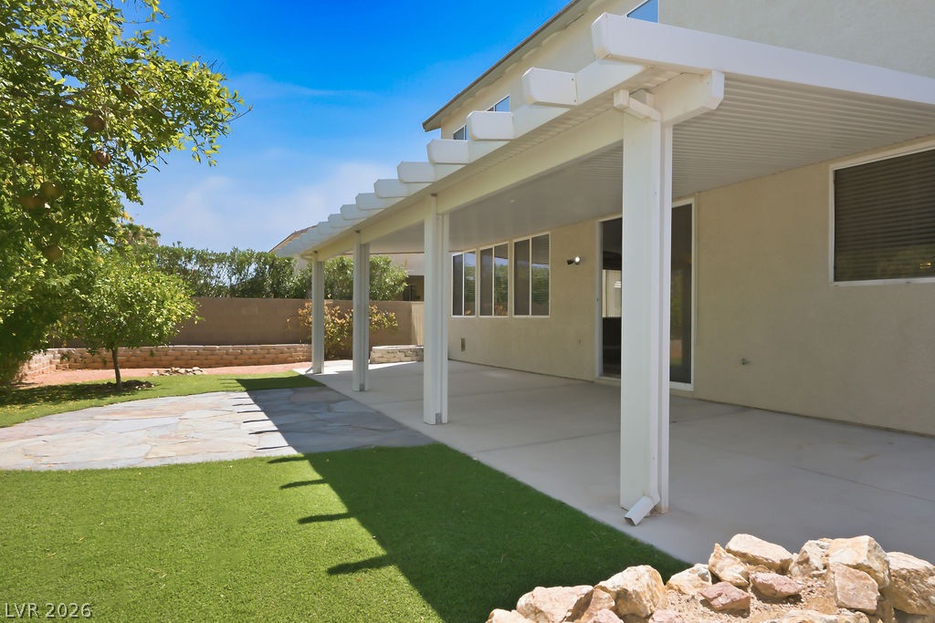 9712 North Running Rabbit Street Las Vegas, NV 89143 - Photo 2 of 42 An inviting covered patio area extends to a manicured lawn, perfect for outdoor relaxation.