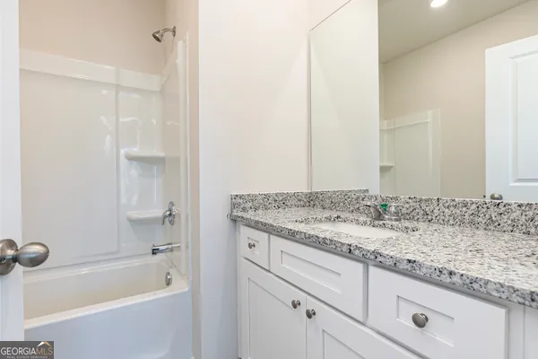 a bathroom with a granite countertop sink and a bathtub