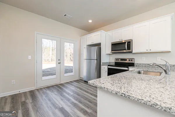 a kitchen with granite countertop a refrigerator stove and microwave