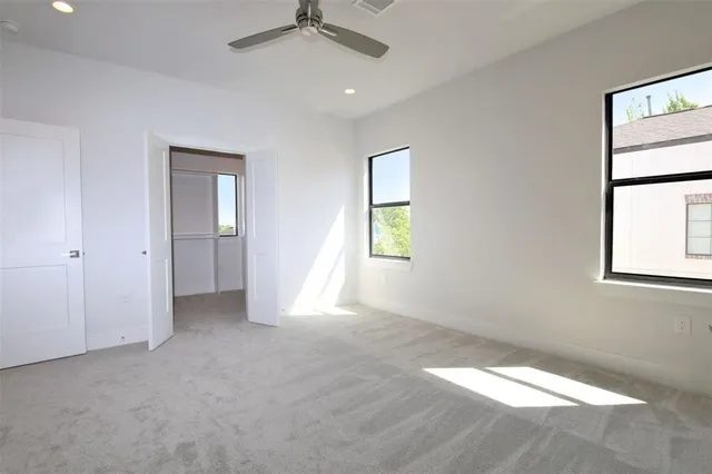 an empty room with windows and fan