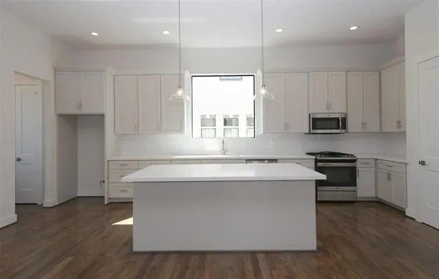 a kitchen with kitchen island a stove a sink and a microwave