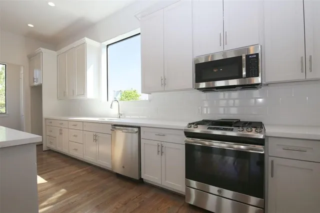a kitchen with stainless steel appliances granite countertop a stove a microwave and white cabinets