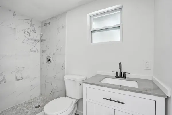 a bathroom with a toilet sink vanity and shower