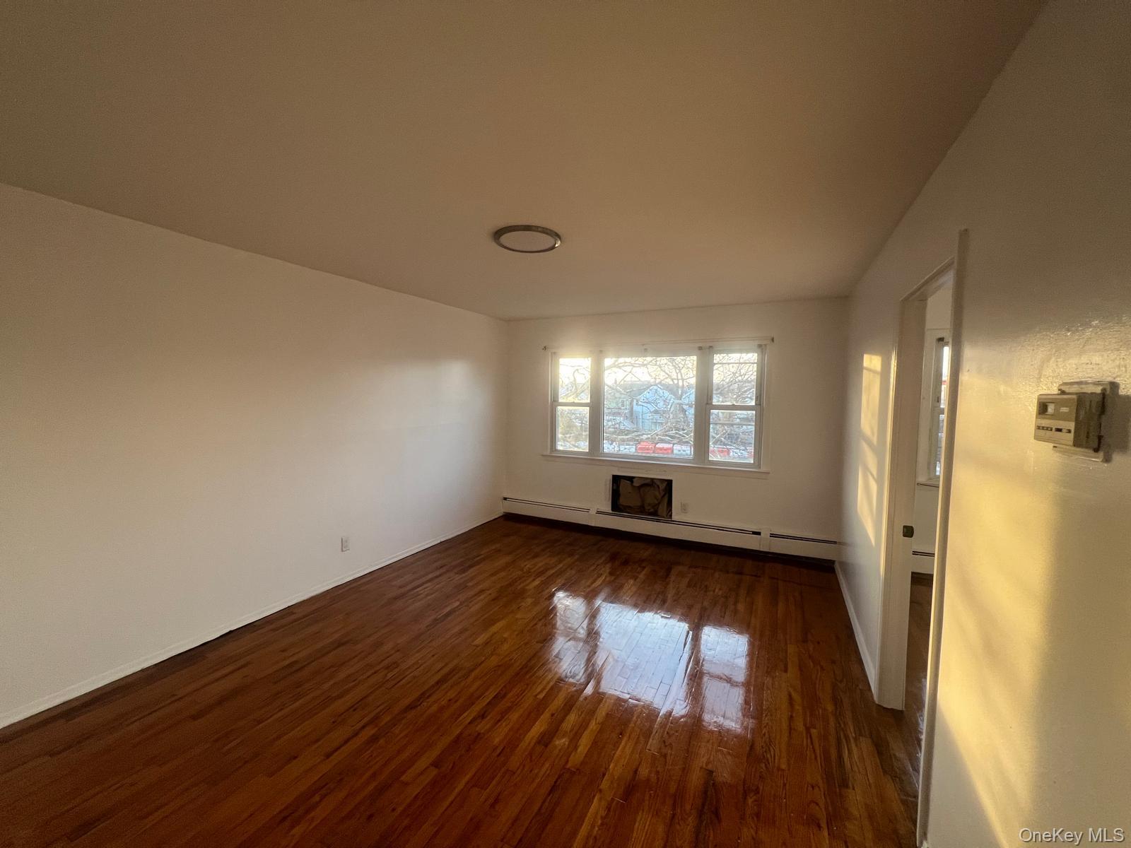 547 Eldert Lane Brooklyn, NY 11208 - Photo 2 of 7 an empty room with wooden floor and windows