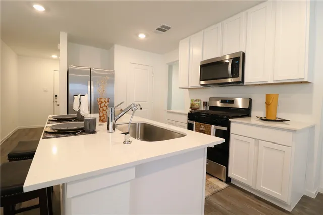 a kitchen with a sink a stove and white cabinets