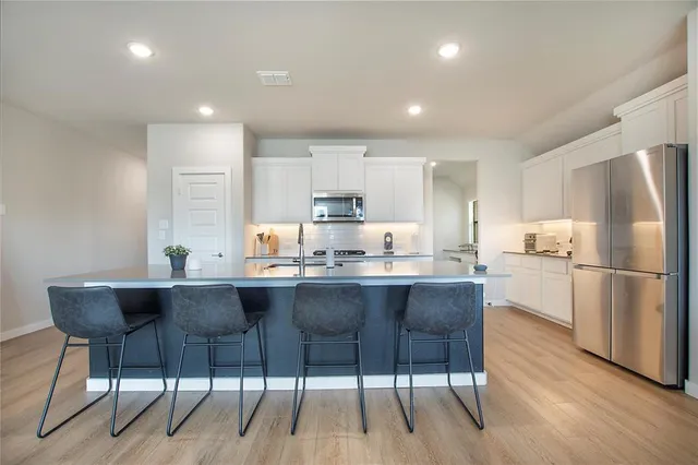 a kitchen with stainless steel appliances granite countertop a dining table chairs refrigerator sink and cabinets