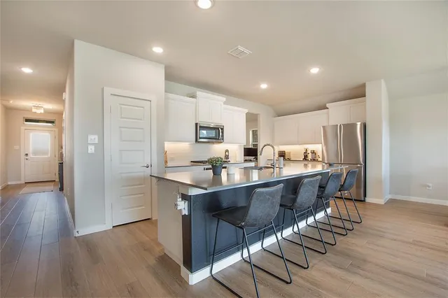 a kitchen with stainless steel appliances granite countertop a kitchen island hardwood floor sink and stove