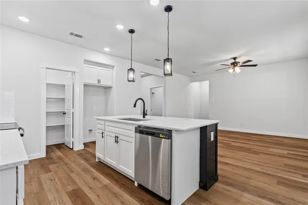 a large white kitchen with kitchen island a sink stainless steel appliances and cabinets