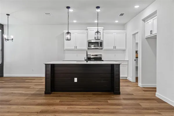 a kitchen with stainless steel appliances granite countertop a sink a stove a refrigerator and island with wooden floor
