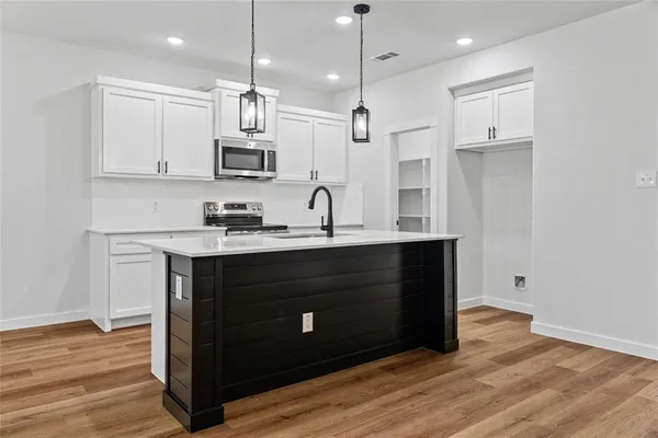 a kitchen with kitchen island granite countertop a sink cabinets and wooden floor