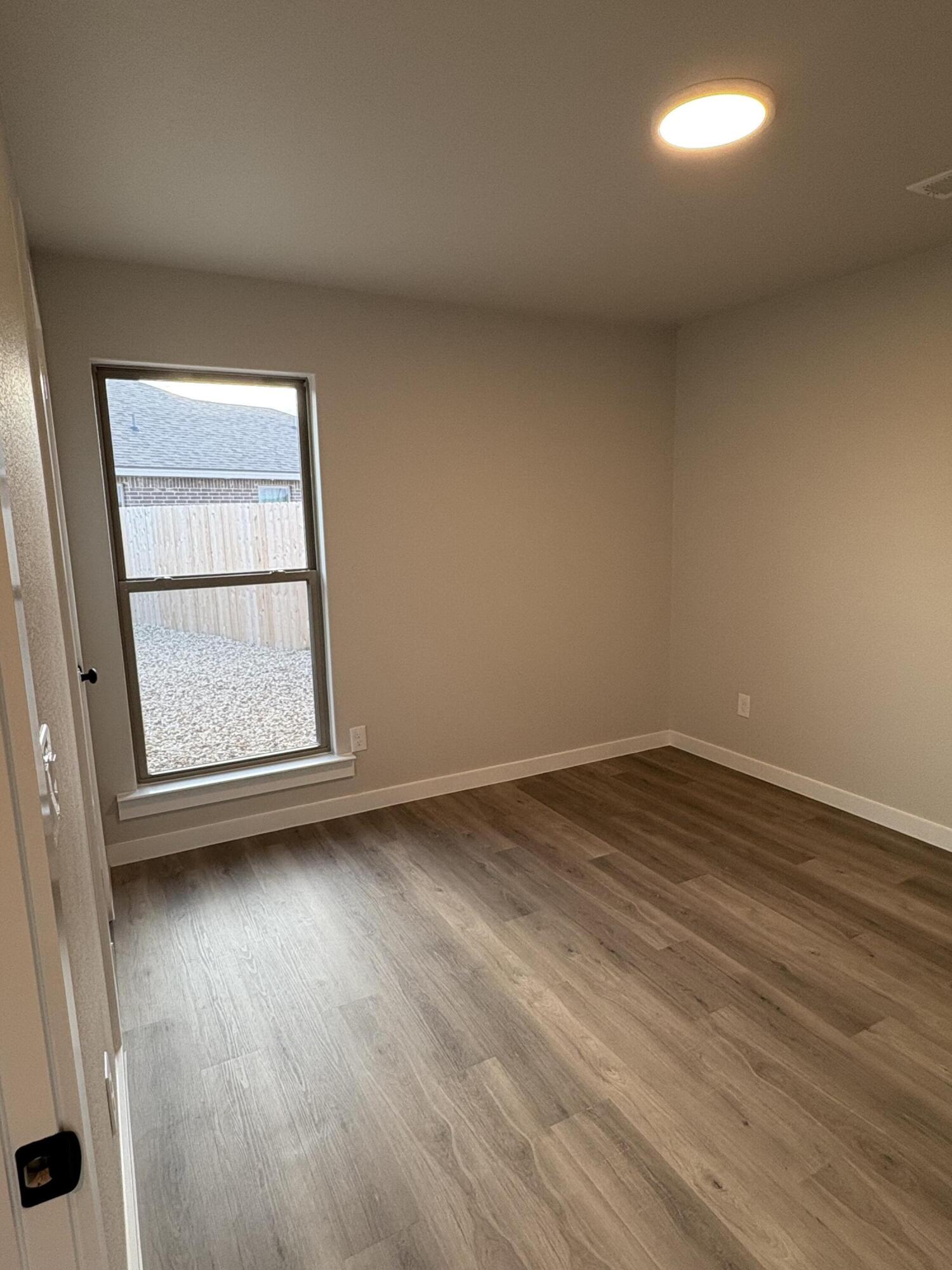 7222 35th Street Lubbock, TX 79407 - Photo 6 of 11 an empty room with wooden floor and windows