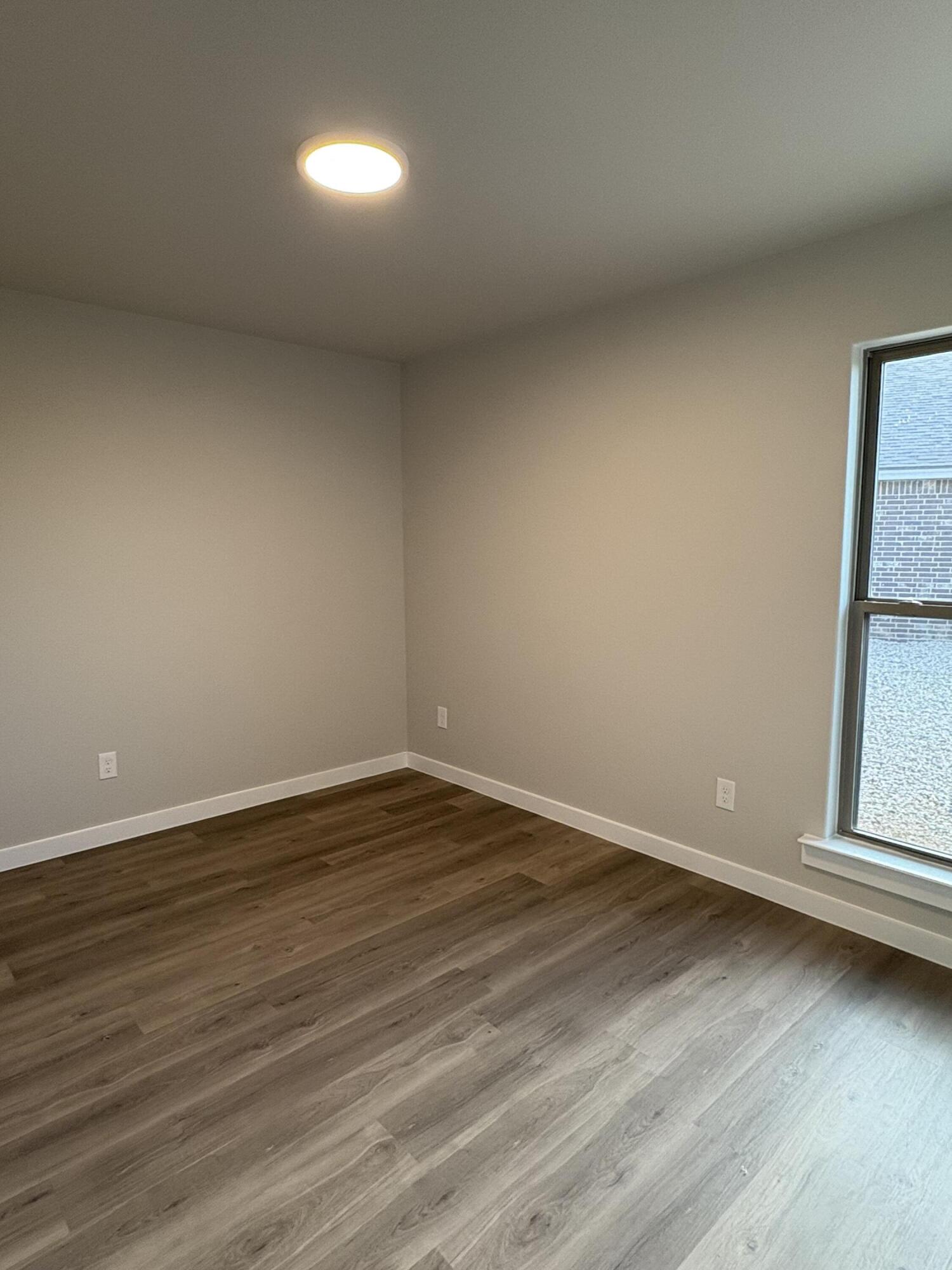 7222 35th Street Lubbock, TX 79407 - Photo 7 of 11 a view of an empty room with wooden floor and a window