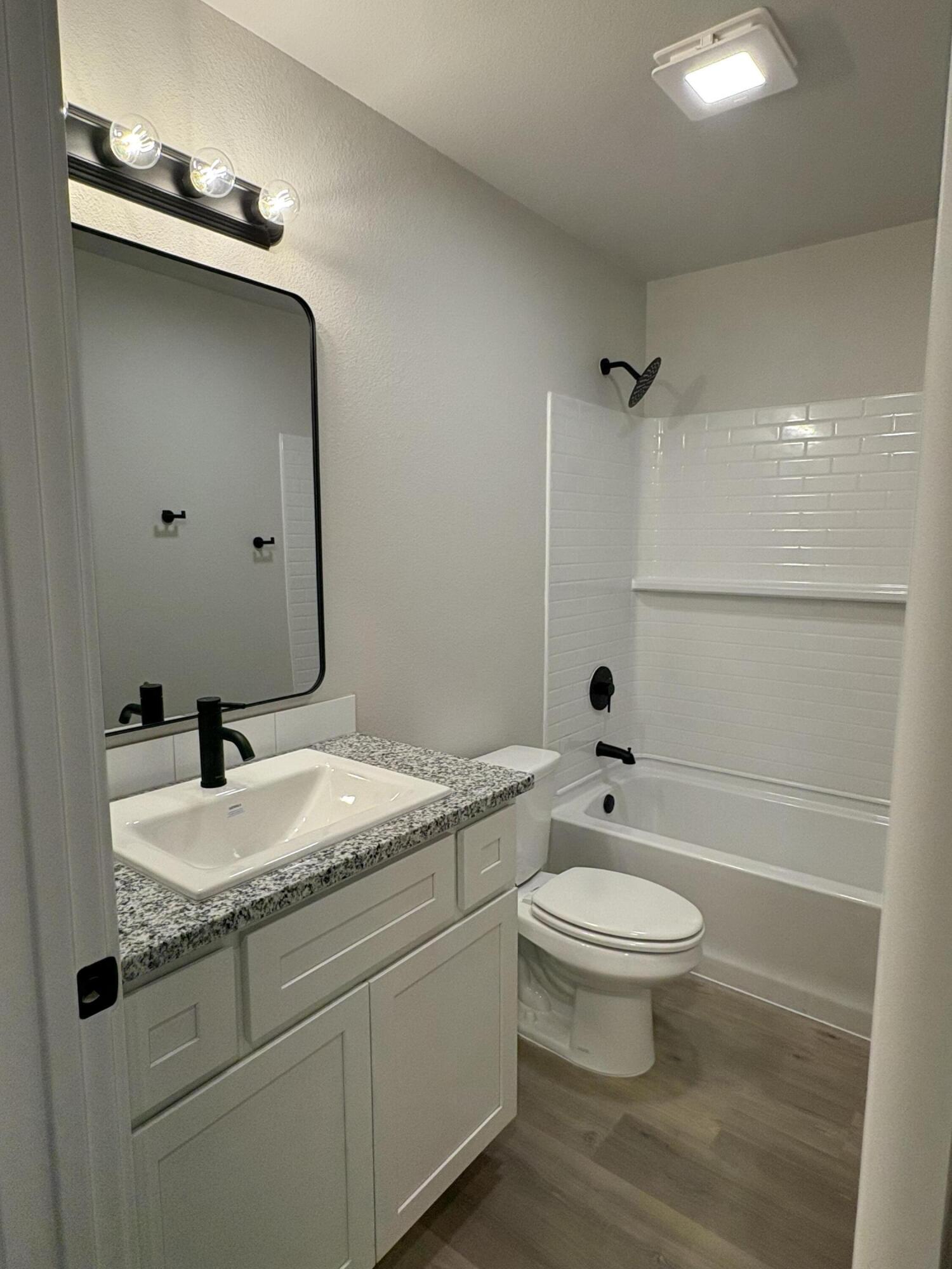 7222 35th Street Lubbock, TX 79407 - Photo 8 of 11 a bathroom with a granite countertop toilet a sink and a mirror