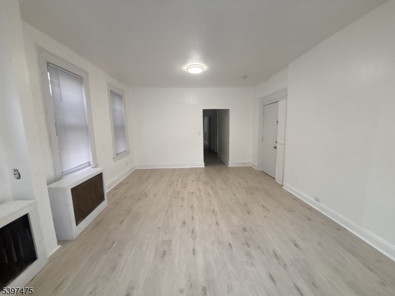 237 Fulton Street Paterson, NJ 07501 - Photo 4 of 11 a view of an empty room with wooden floor and a fireplace