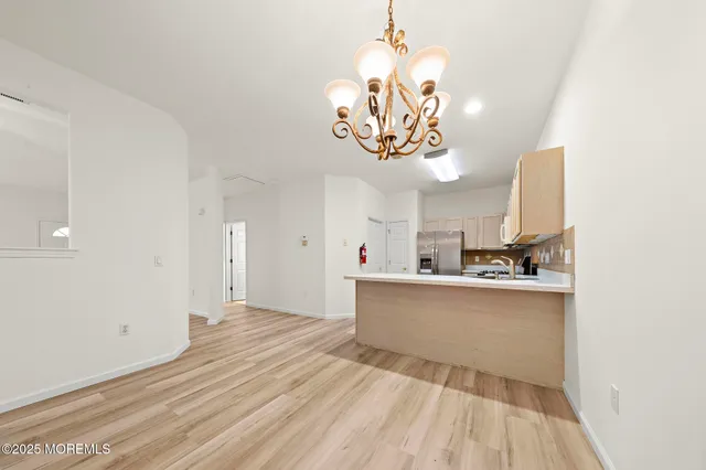 a view of a kitchen with a sink stainless steel appliances and chandelier