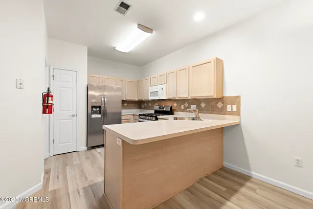 a kitchen with a sink a refrigerator and white cabinets