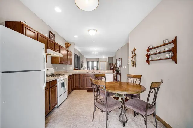 a kitchen with stainless steel appliances granite countertop a dining table chairs stove and a refrigerator