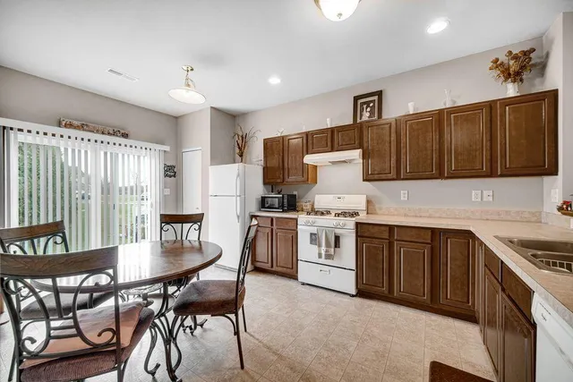 a kitchen with granite countertop a table chairs microwave and cabinets