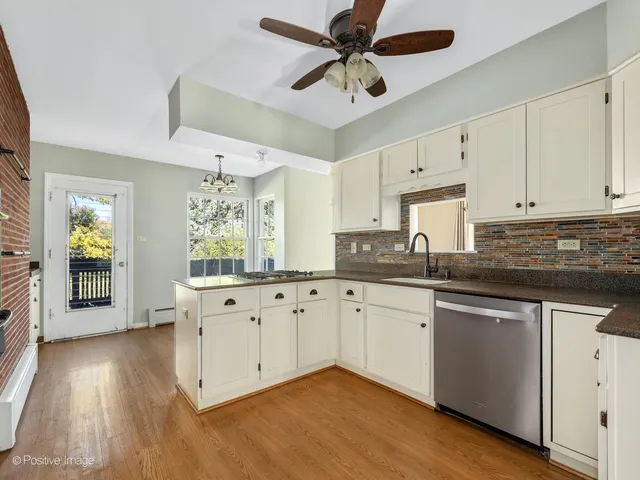 a kitchen with granite countertop a stove a sink and white cabinets with wooden floor