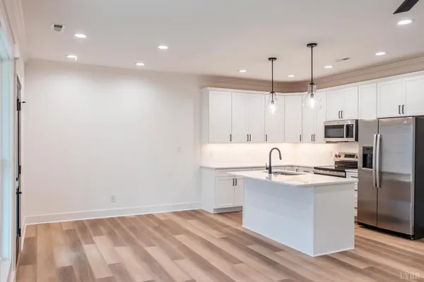 a view of kitchen with white cabinets and a window