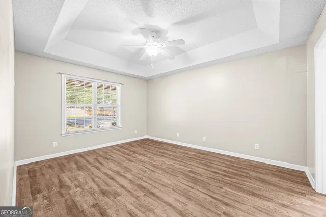 an empty room with wooden floor fan and windows