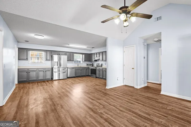 a view of a kitchen with wooden floor and a kitchen space with a sink