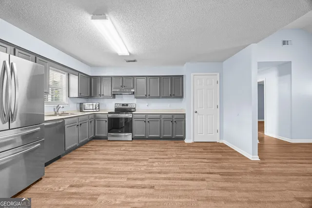 a kitchen with a white cabinets and wooden floor