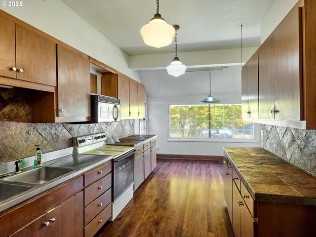 a kitchen with kitchen island granite countertop wooden floors wooden cabinets a counter and a sink