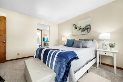 a bedroom with a large bed and a lamp on dresser