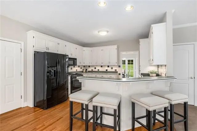 a kitchen with stainless steel appliances a dining table chairs refrigerator and cabinets