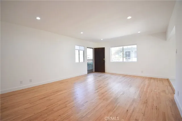 a view of an empty room with wooden floor and window