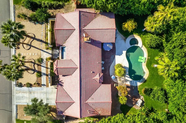 an aerial view of a house with swimming pool and large trees