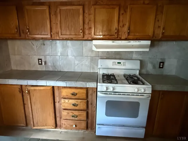 a kitchen with granite countertop a stove top oven and cabinets