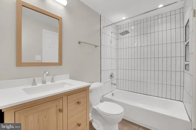 a bathroom with a bathtub shower sink vanity mirror and toilet