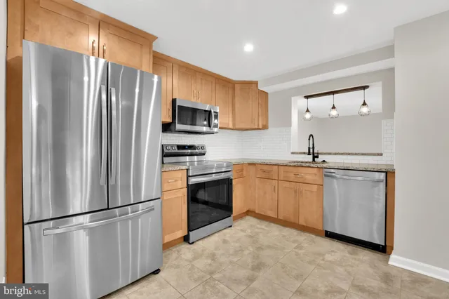 a kitchen with stainless steel appliances granite countertop a refrigerator sink and stove