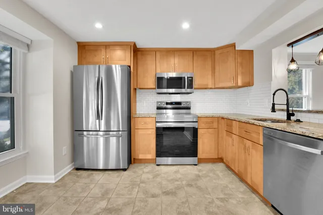 a kitchen with stainless steel appliances granite countertop a refrigerator sink and stove