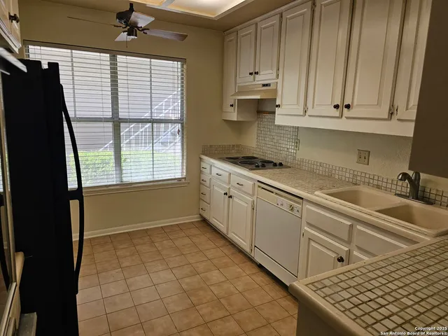 a kitchen with stainless steel appliances granite countertop a refrigerator a sink dishwasher and white cabinets with wooden floor