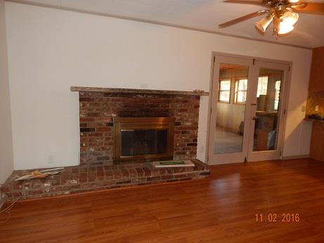1116 Fall River Road Lawrenceburg, TN 38464 - Photo 6 of 16 an empty room with wooden floor fireplace and windows